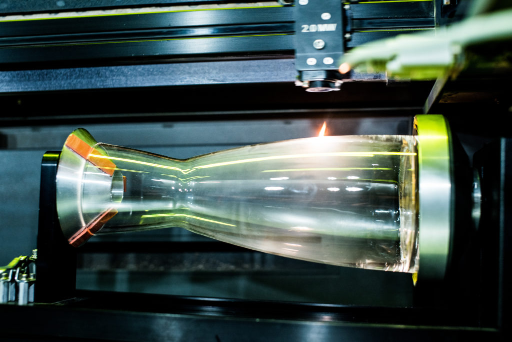 Eine Wasserkaraffe wird gerade mittels Lasergravur mit einem Logo versehen