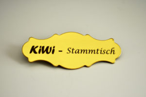 Gelber Anstecker mit dem Schriftzug Kiwi - Stammtisch